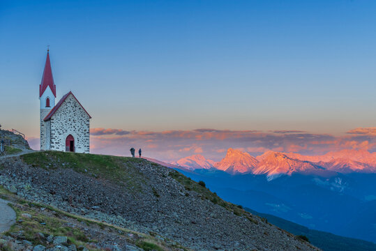 Man enjoys sunset over Dolomites at the pilgrimage church of Lazfons, Chiusa, Bolzano district, South Tyrol, Italy