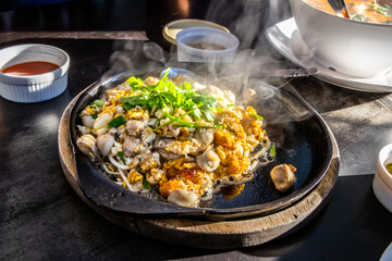 Hot pan of crispy fried oyster omelette served with bean sprout and spicy sauce.