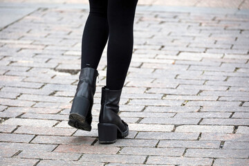 Female legs in black warm pantyhose and shoes on high heels. Girl walking down a street, fashion in...