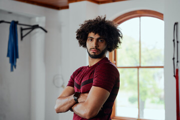 Fototapeta na wymiar Portrait of focused young middle eastern man with arms crossed at the gym