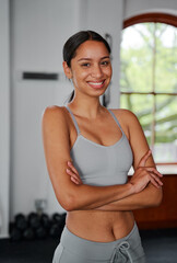 Fototapeta na wymiar Confident young biracial woman looking at camera with arms crossed at the gym