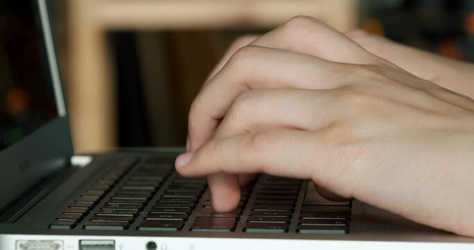 Female hands typing fast on laptop keyboard, closeup