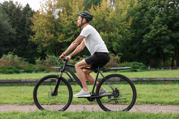 Obraz premium Man riding bicycle on road at park
