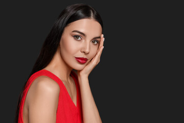 Portrait of young woman wearing beautiful red lipstick on black background, space for text