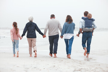 Obraz premium Holding hands, walking and big family on the beach for exercise while on summer vacation. Grandparents, parents and children on outdoor walk in nature by ocean while on holiday, adventure or journey.