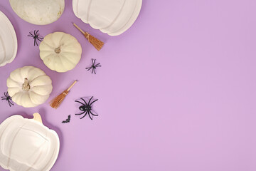 Halloween party flat lay with pumpkin shaped plates, pumpkins, witch broom, spiders and coffins on...