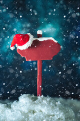 Wooden pointer and Santa's hat on the background of the night starry sky.