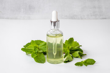 Green mint leaves with bottle of essential peppermint oil