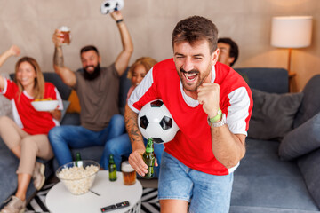Football fans celebrating their team victory while watching the game on TV