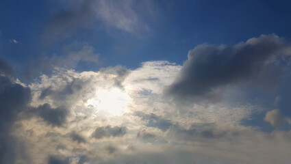 Naklejka na ściany i meble Sun behind the clouds on sky background