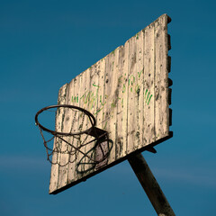 old outdoor basketball hoop against blue sky background