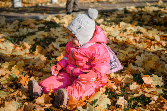 baby little girl sitting on the ground on yellow leaves in autumn
