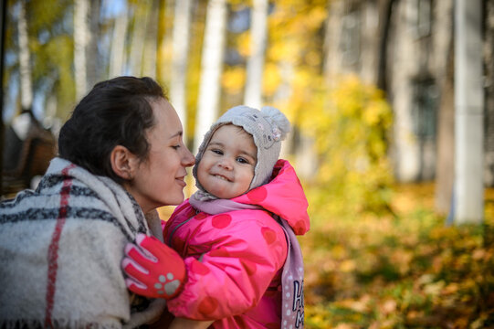 young mom with little daughter in the park in autumn close-up