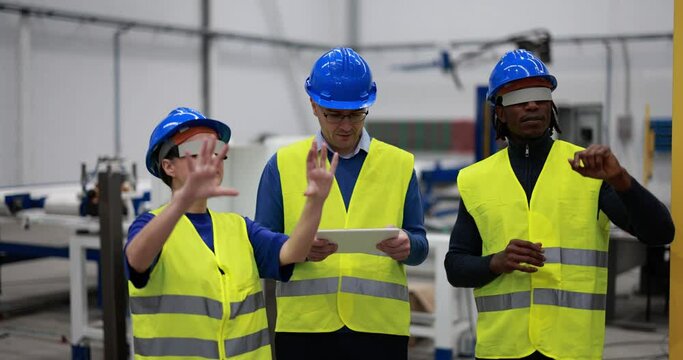 Multiethnic engineers using futuristic augmented reality glasses inside robotic factory