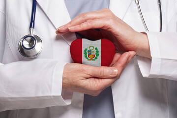Peruvian doctor holding heart with flag of Peru background. Healthcare, charity, insurance and...