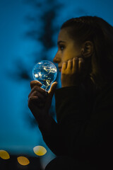 young worried woman holding bright shining lightbulb in her hands feeling unsave while in fear...