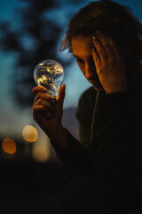 young worried female human holding bright shining lightbulb in her hands feeling unsave while...