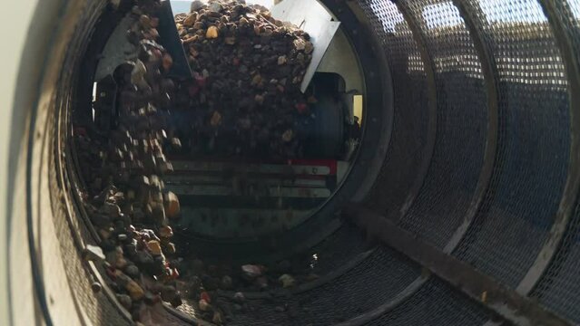 Stones Mechanical Screening - gravel with soil and sand falls from the belt conveyor to spinning cylindrical sifter with holes  sifting of soil, crushed stone and other loose building materials
