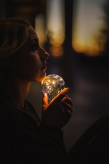 young worried female human holding bright shining lightbulb in her hands feeling unsave while...