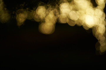 Blurry glowing bokeh lights highlighted on a black isolated background. Festive golden glowing...