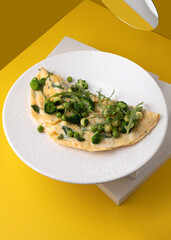 amlet with egg and greens on a white plate on a yellow background