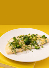 amlet with egg and greens on a white plate on a yellow background