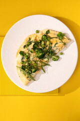 amlet with egg and greens on a white plate on a yellow background