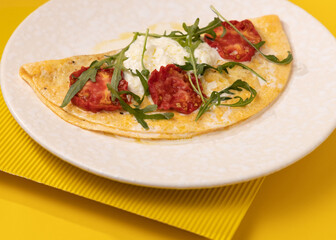 amlet with egg and greens on a white plate on a yellow background