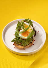 toast with egg and greens on a yellow background