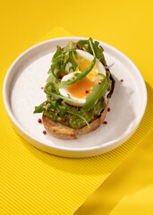 toast with egg and greens on a yellow background