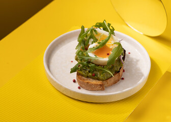 toast with egg and greens on a yellow background