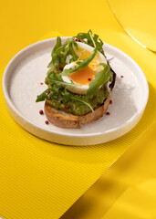 toast with egg and greens on a yellow background
