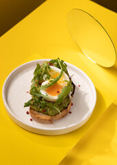 toast with egg and greens on a yellow background