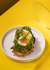toast with egg and greens on a yellow background