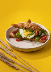 croissant with egg on a yellow background