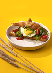 croissant with egg on a yellow background