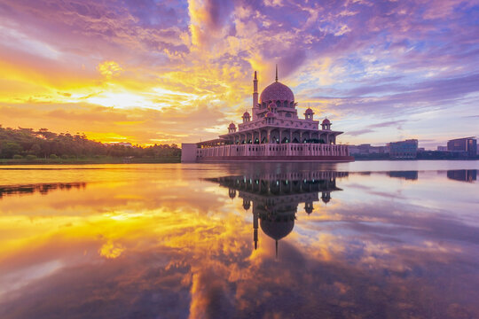 Beautiful sunrise At Putra Mosque, Putrajaya Malaysia with colorful clouds and reflection on the lake surface.