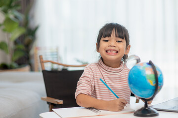 Asian little girl is learning the globe model, concept of save the world and learn through play activity for kid education at home.