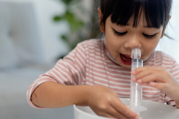 Little asian girl saline nasal wash nose at home.