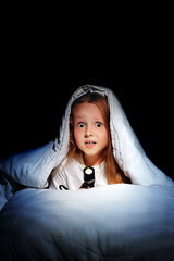 Girl under the blanket with a flashlight in hands