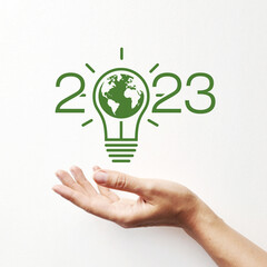 inscription: 2023 with an image of a light bulb and a planet in it. A symbol of environmental...
