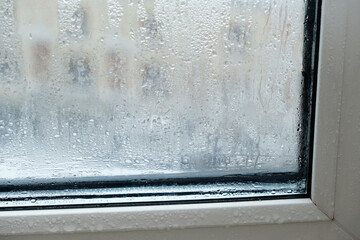 Drops and condensation on the window. Fogged window, fragment plastic frame, close-up. Increased...