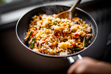 cooking tasty rice and vegetable mix with corn, pea, beans in pan on kitchen