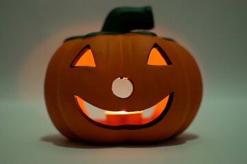 A closeup of a Halloween Jack O Lantern lit by a candle isolated on a white background.