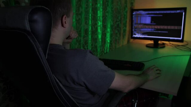 Programmer writes web html code virus. Password hacking. Tester looks for bugs errors. Freelancer. Online programming language training. Student is sitting in chair at home at night. Cyber security