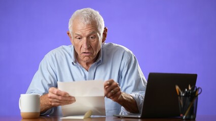 Fototapeta premium Angry stressed elderly man 70s, opening envelope reading bad news in mail letter. Mad man feels frustrated about high bills, bank debt, tax invoice or mistake isolated on purple background