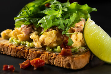 Delicious crispy toast with omelet, arugula, avocado, with lime sauce