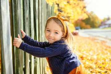 Adorable two years old girl enjoying nice and sunny autumn day outdoors