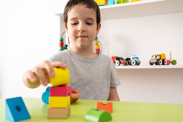 Child playing with colourful educational toy blocks on the table at preschool or kindergarten. Kid...