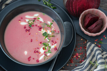 beetroot soup with chili flakes and thyme, homemade and served in black bowl